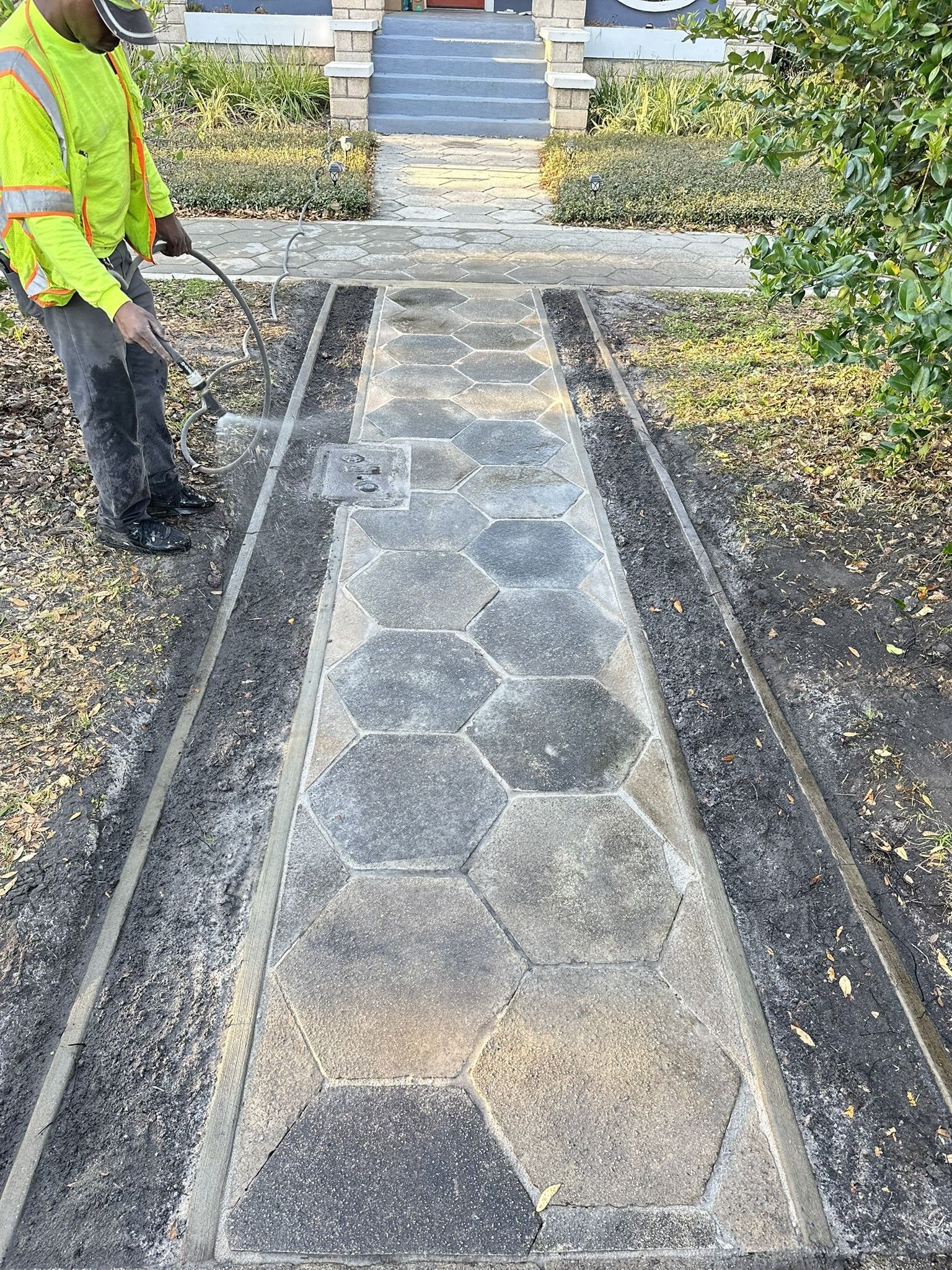 A man is standing on a paver walkway in front of a house.