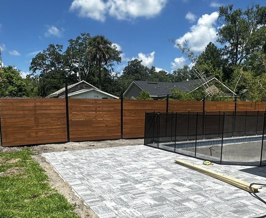 A wooden fence surrounds a swimming pool in a backyard