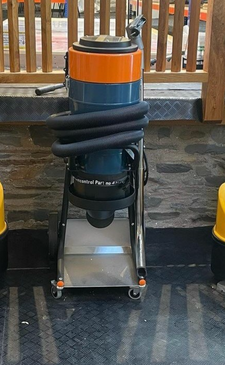 A blue and orange vacuum cleaner is sitting on a concrete floor.