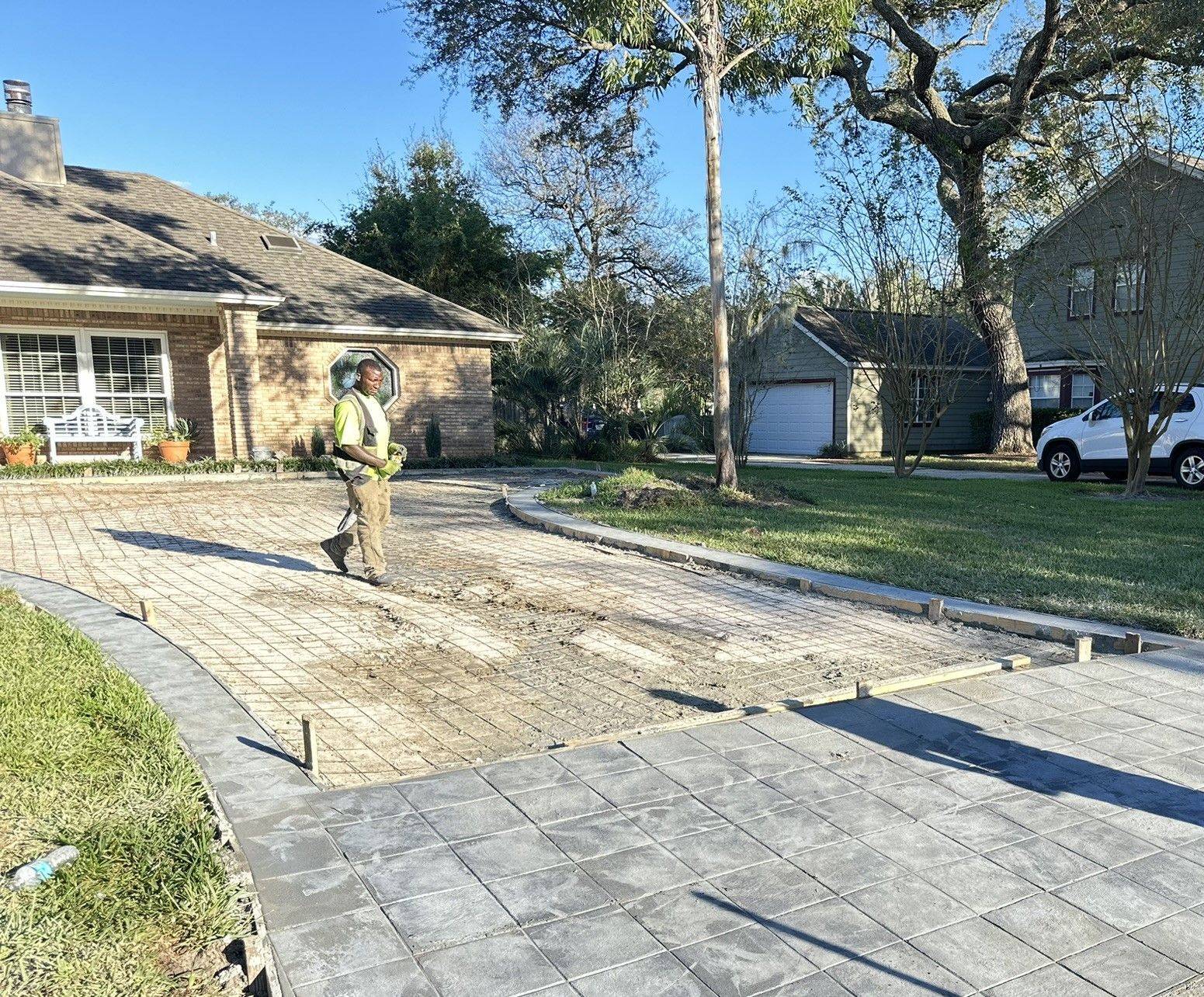 Worker installing stamped concrete on a driveway in front of a house.