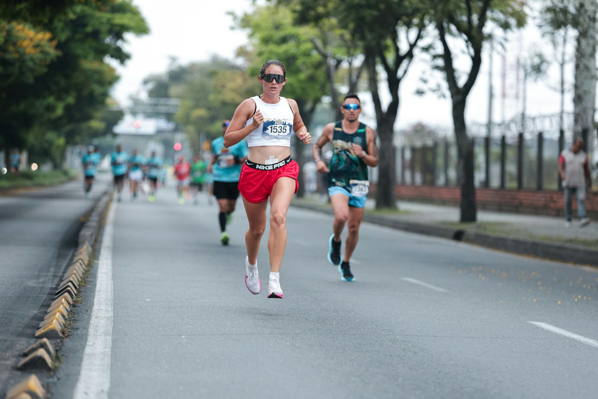 Runners in a race on a city street. Woman in red shorts leading, others follow.