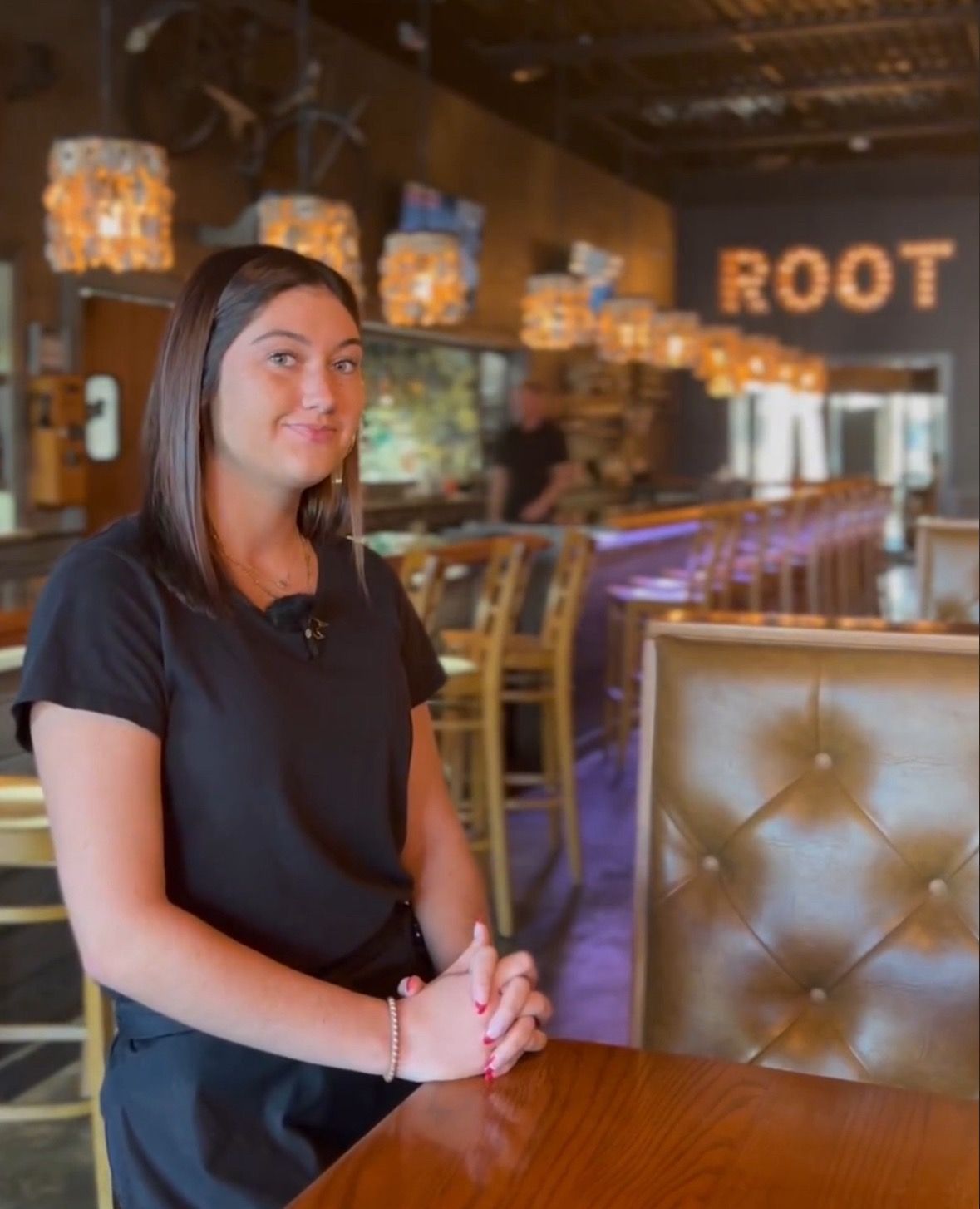 A woman is sitting at a table in front of a sign that says root