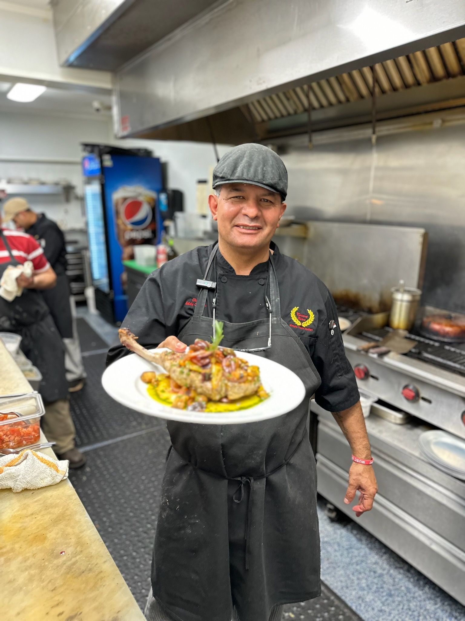 A chef is holding a plate of food in a kitchen.