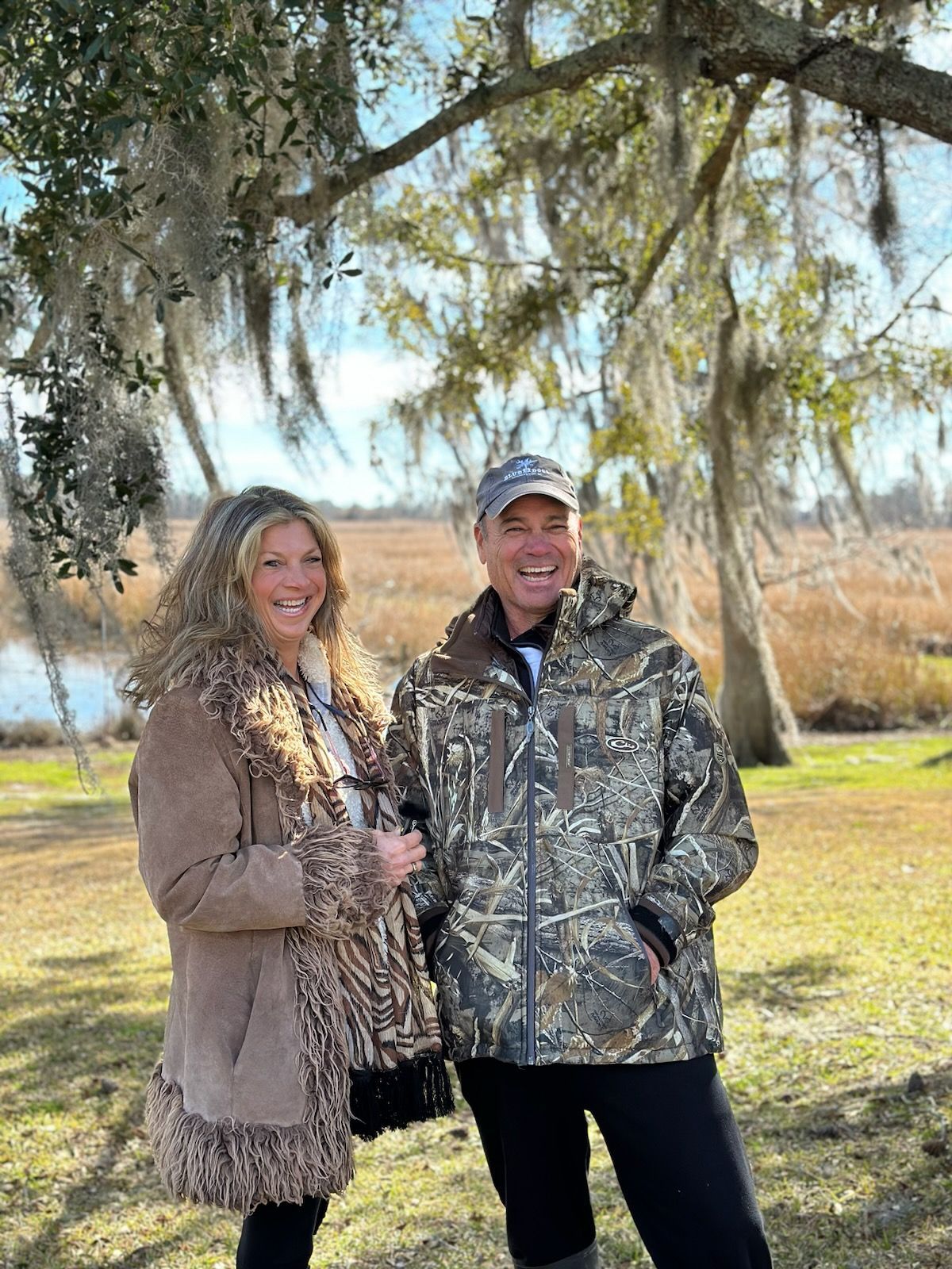 A man and a woman are standing next to each other in front of a tree.