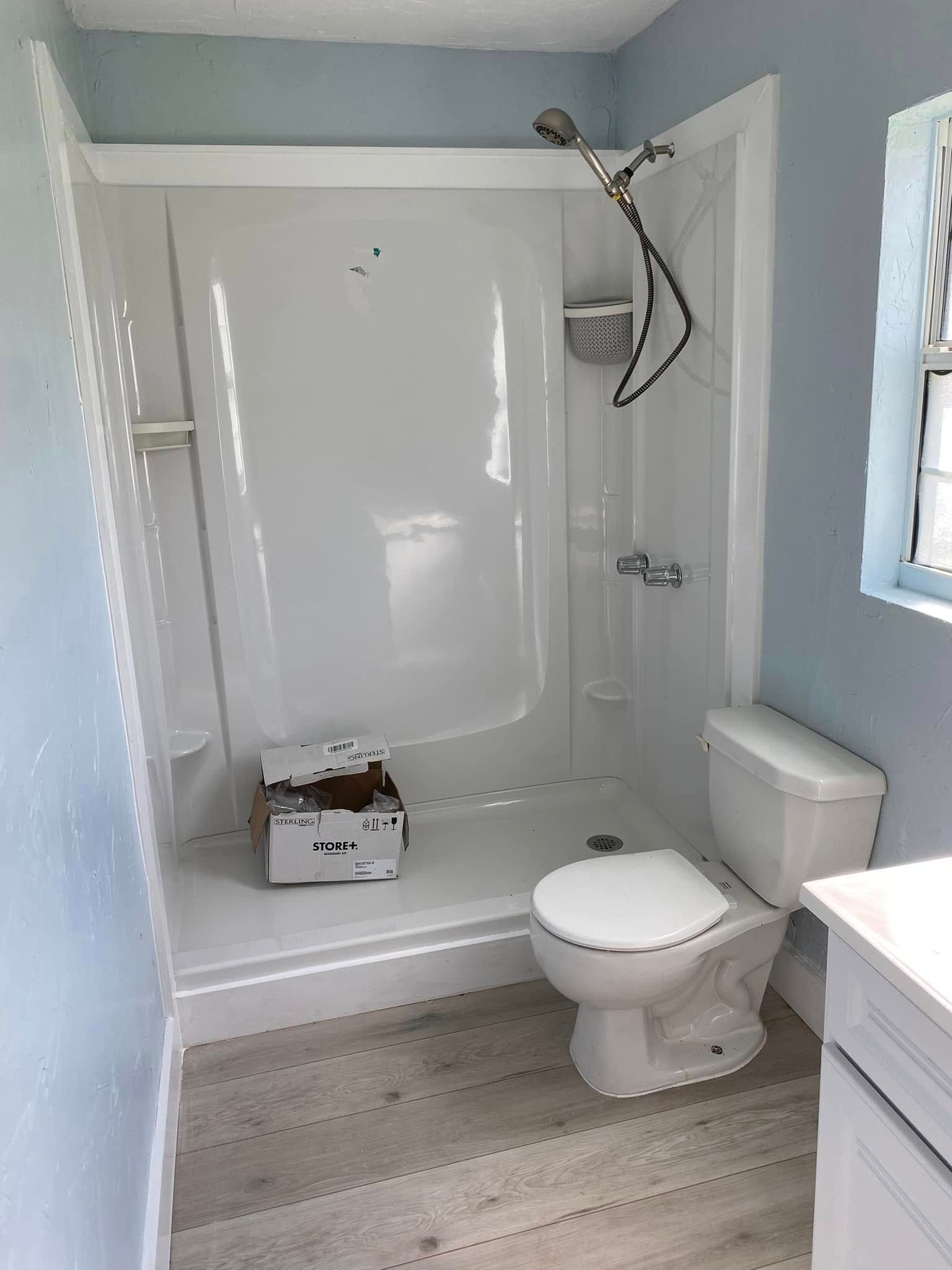 A bathroom with a toilet , shower and sink.