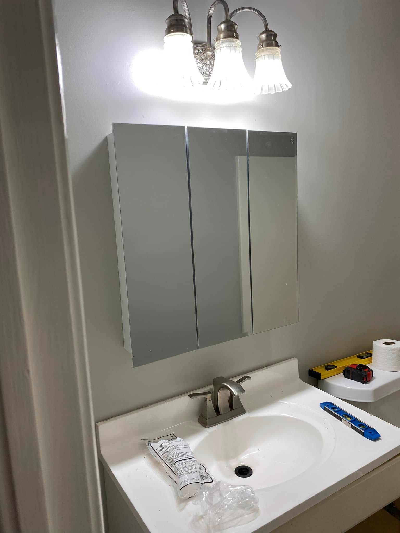 A bathroom with a sink , mirror and light fixture.