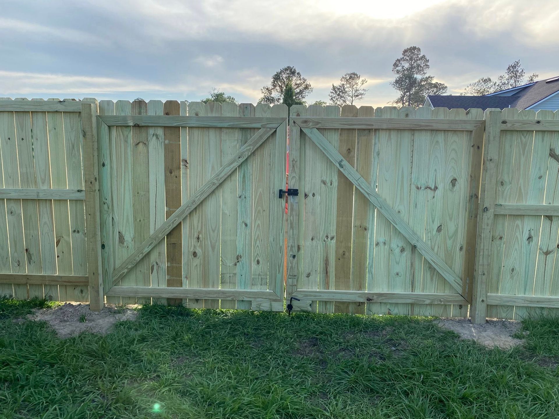 A wooden fence with a gate in the backyard of a house.