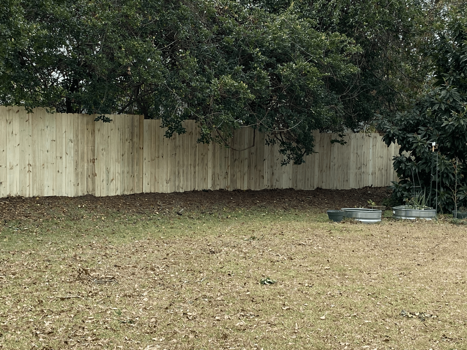 A wooden fence surrounds a lush green field.