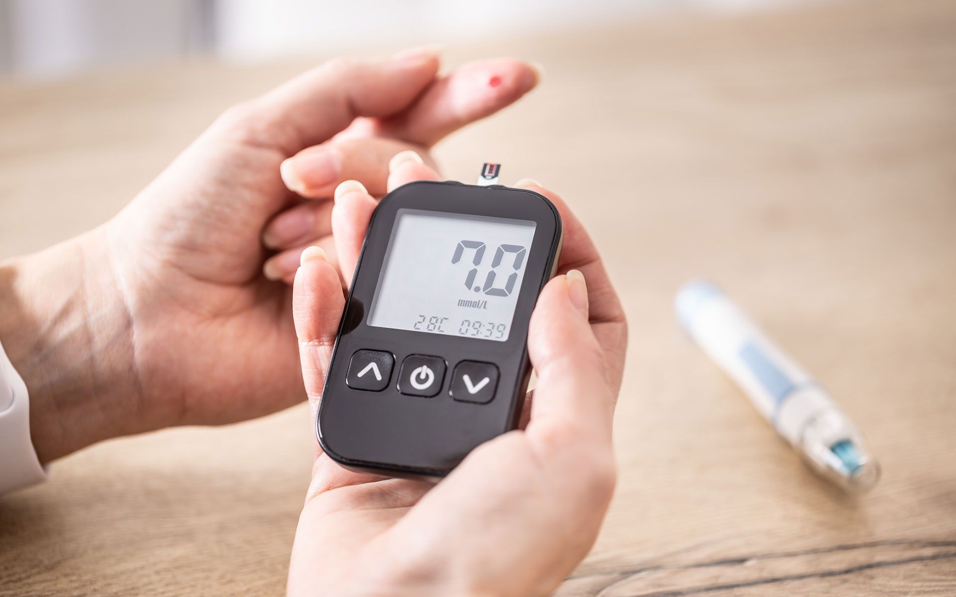 Person testing blood sugar with a glucose meter; reading is 7.0.