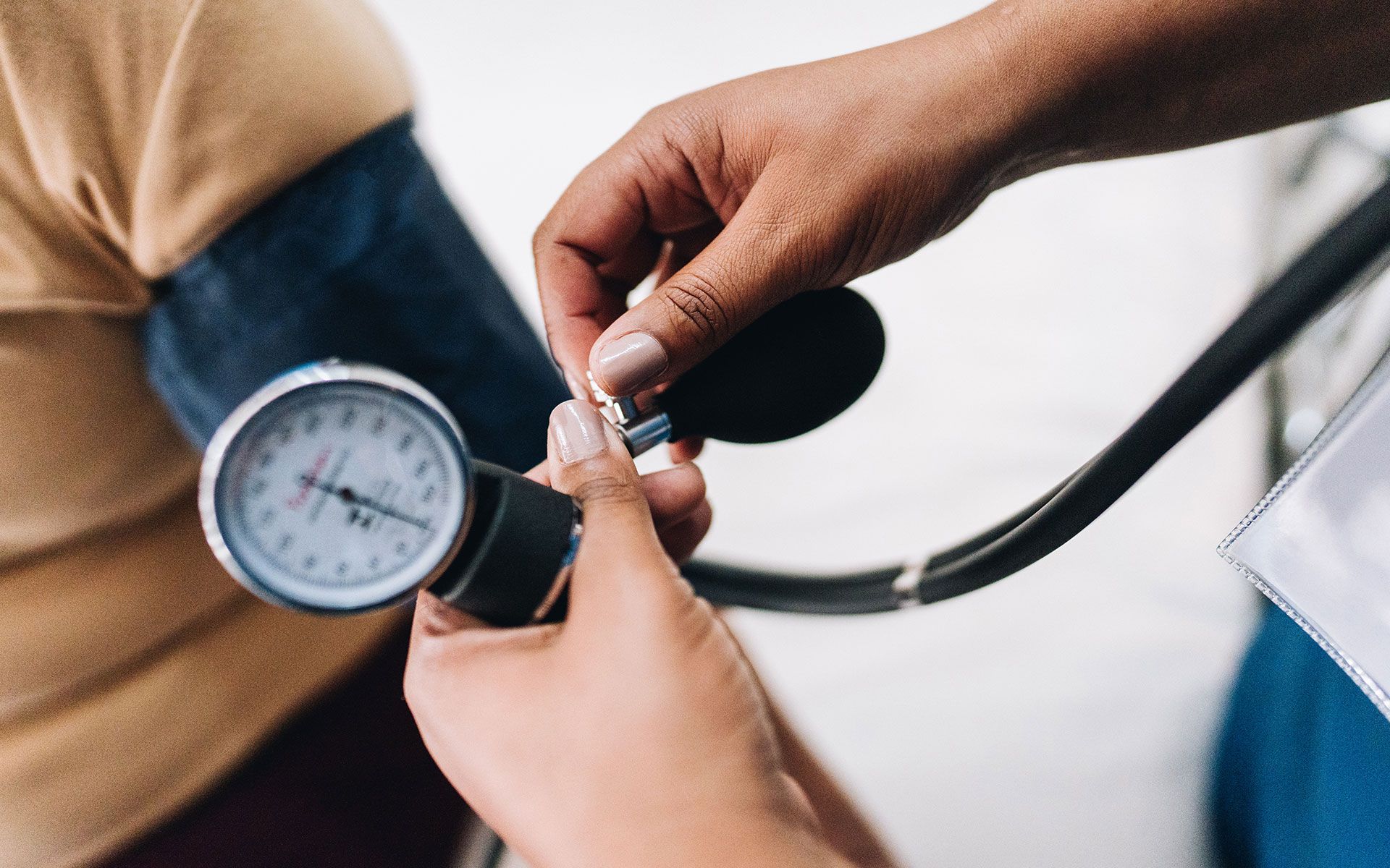 A person's blood pressure being measured with a stethoscope and gauge on their upper arm.
