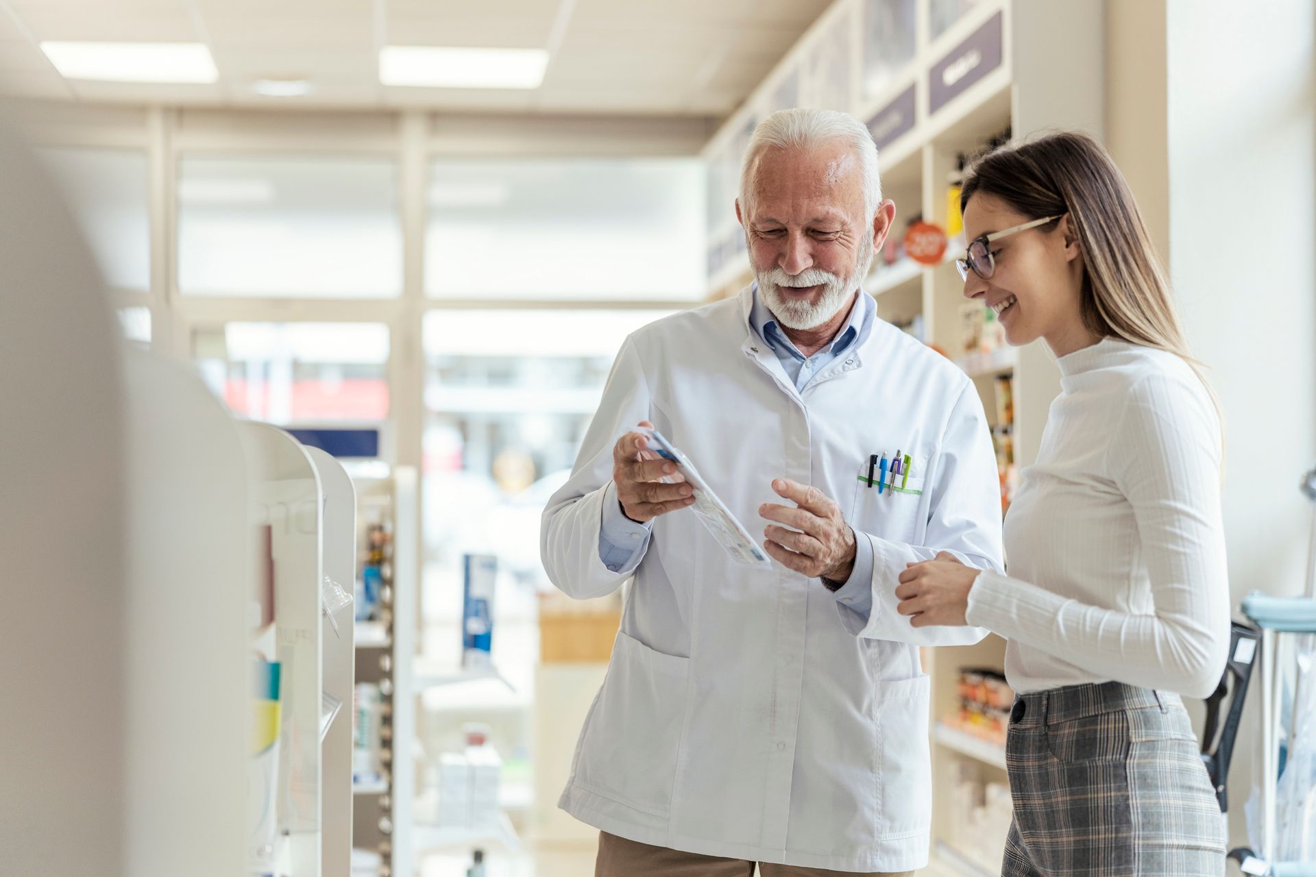 Pharmacist showing prescription to woman in a pharmacy.