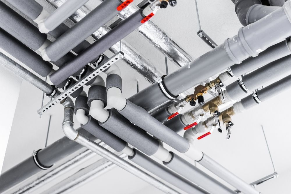 A Bunch Of Pipes Are Hanging From The Ceiling Of A Building — Warrnambool Emergency Plumbing in Warrnambool, VIC