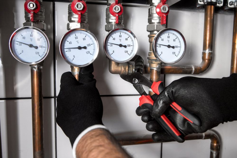 A Plumber Is Working On A Pipe With A Pair Of Pliers — Warrnambool Emergency Plumbing in Warrnambool, VIC