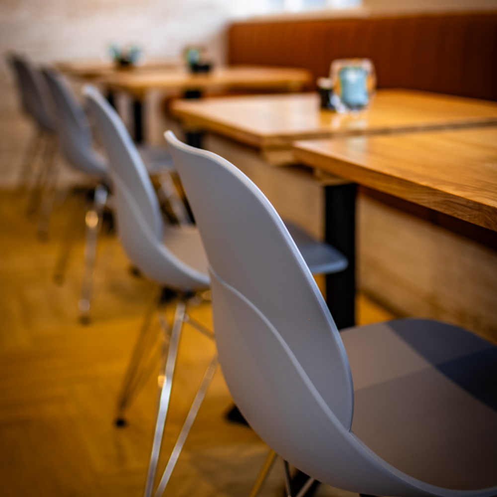 Empty restaurant seating with gray chairs and wooden tables.