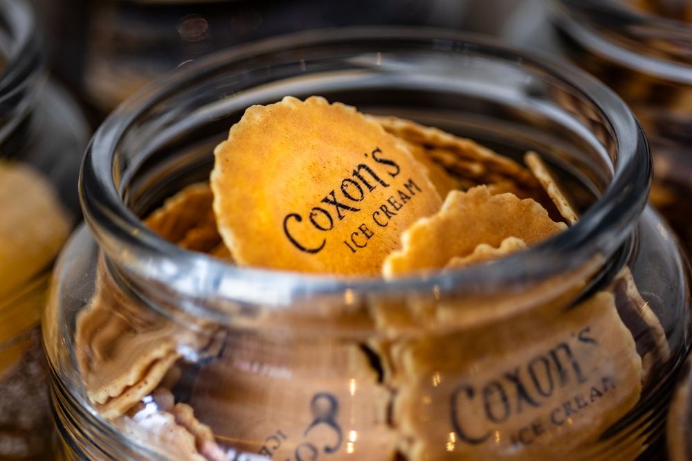 Jar of Coxon's Ice Cream wafers, close-up. Wafers are golden brown and scalloped.