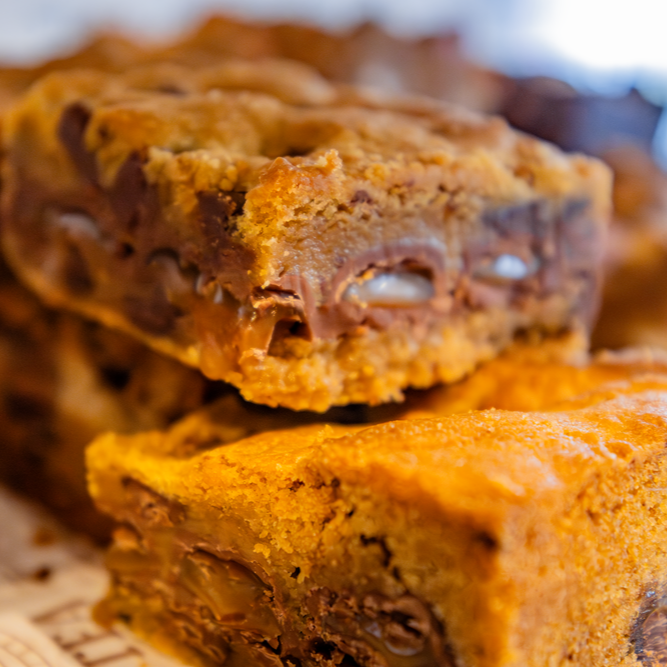 Close-up of caramel-filled cookie bars with chocolate chips, stacked.