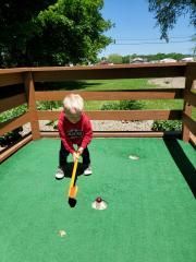 A young boy is playing a game of mini golf.