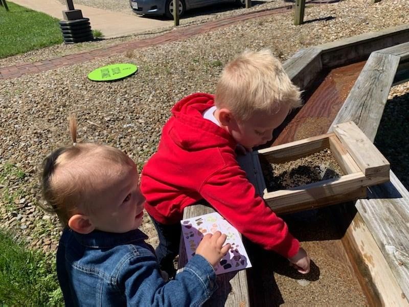 A boy and a girl are playing in a sandbox.