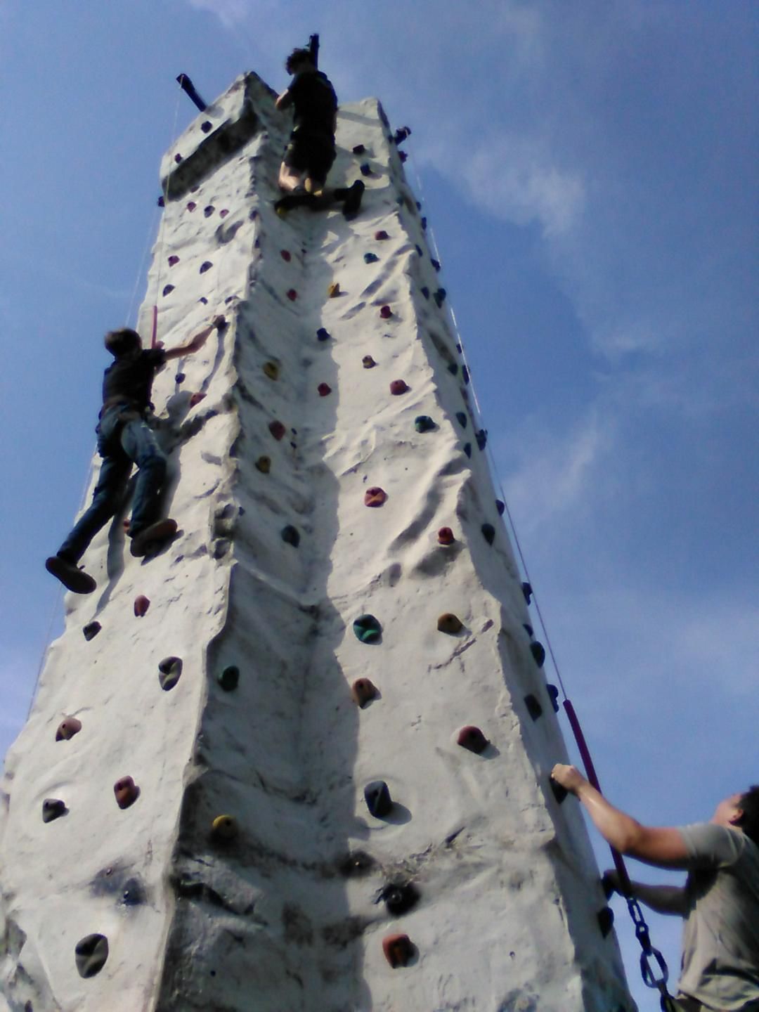 A group of people are climbing up a climbing wall
