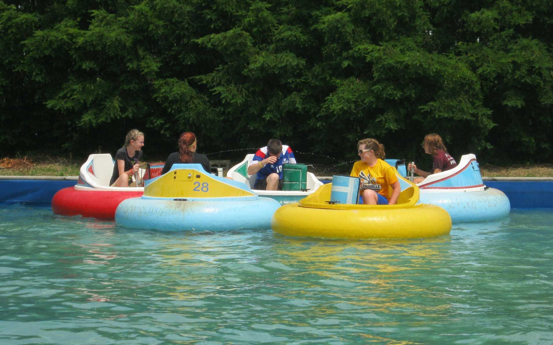 A group of people are riding bumper boats in a pool.