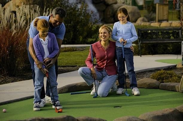 A family is playing mini golf in a park.