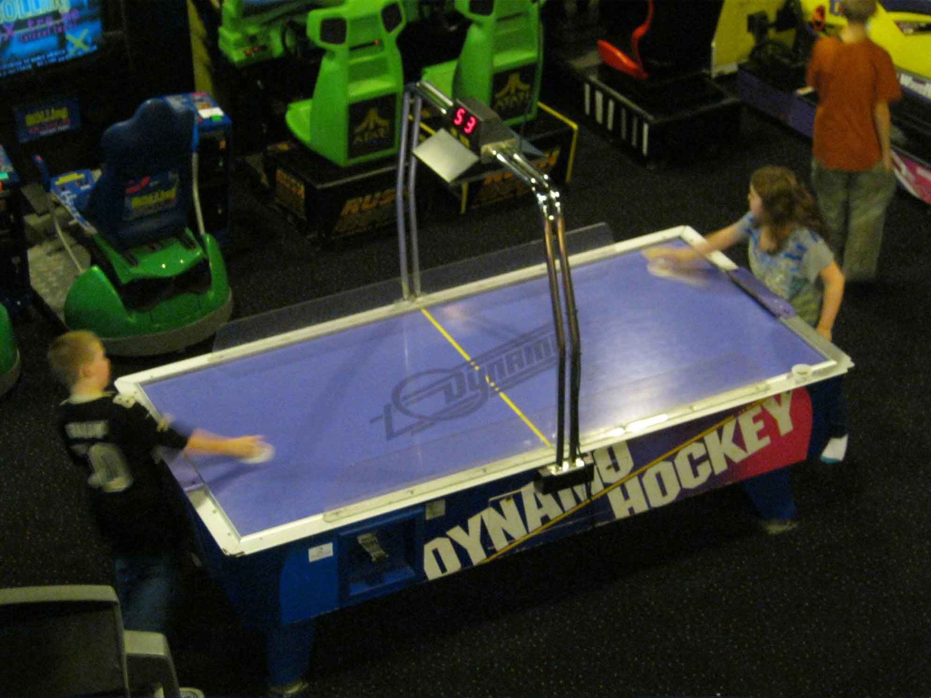 A boy wearing a number 3 jersey is playing air hockey