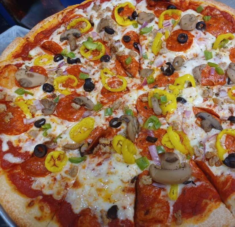 A pizza with pepperoni , mushrooms , onions and olives on it
