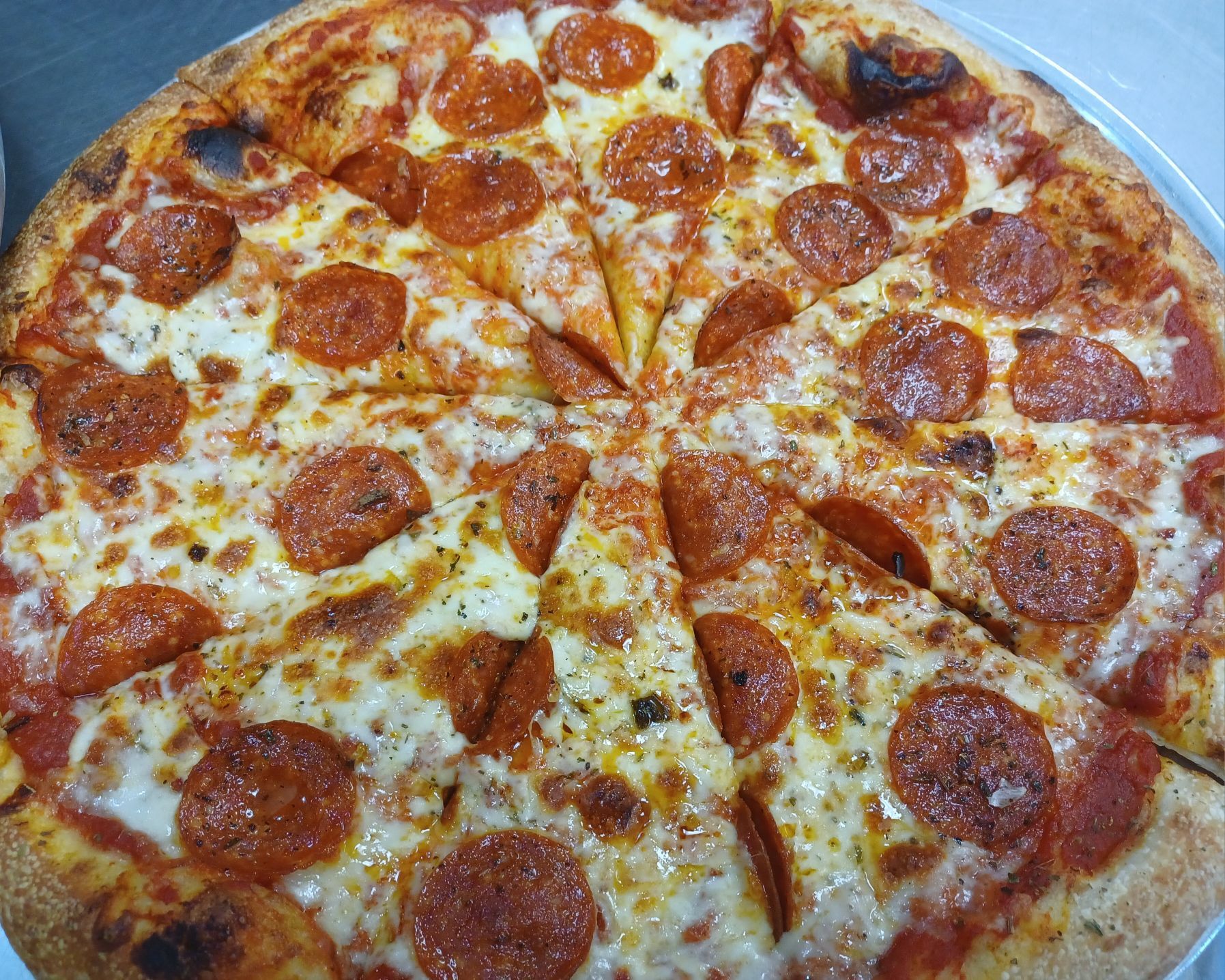 A pepperoni pizza with cheese and pepperoni slices on a white plate.