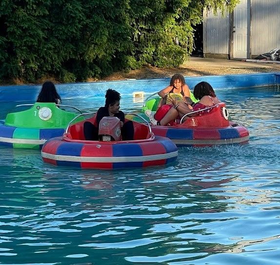 A group of people are riding bumper boats in a pool.