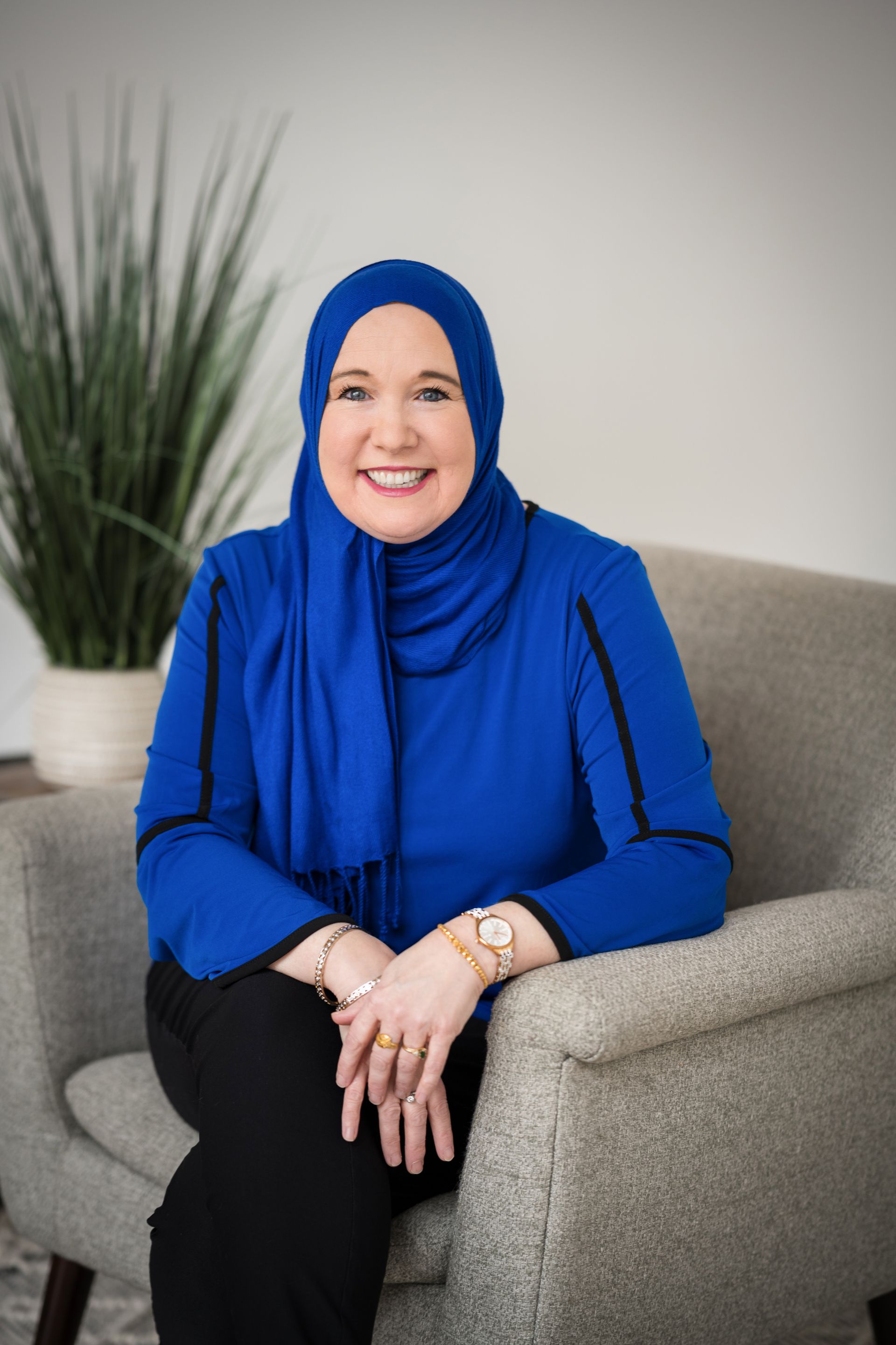 A woman is sitting at a desk with a laptop and a vase of flowers.