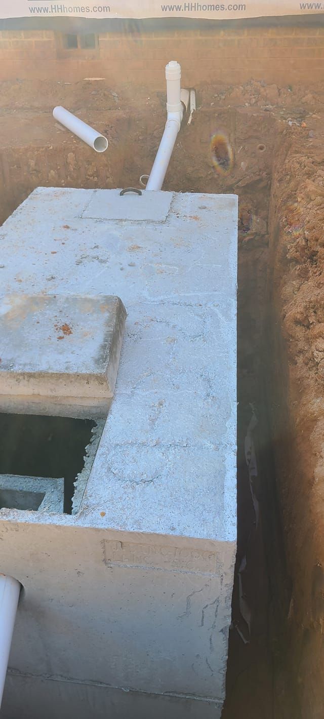 A concrete block is sitting in the middle of a dirt field next to a pipe.