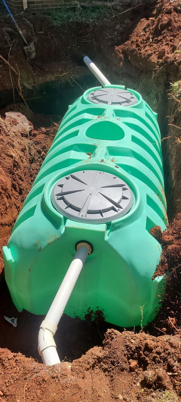 A green septic tank is sitting in the dirt.