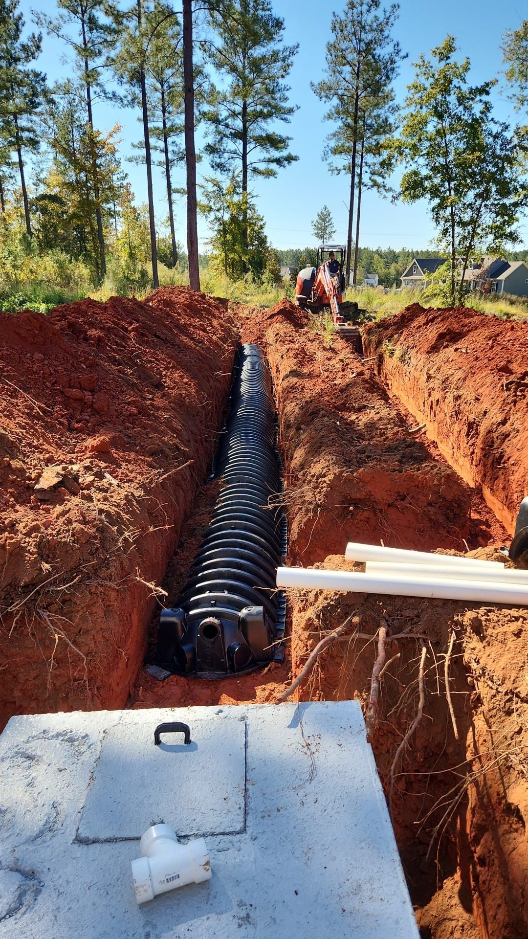 A man is digging a hole in the ground to install a septic system.