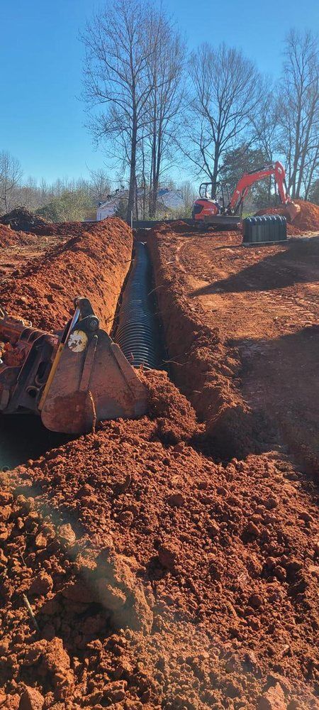An excavator is digging a trench in the dirt on a construction site.