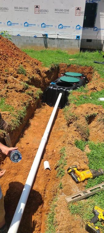 A man is installing a septic system in a yard.