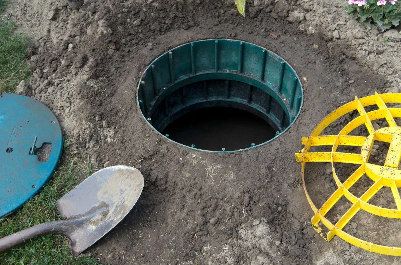 A shovel is sitting next to a hole in the ground.