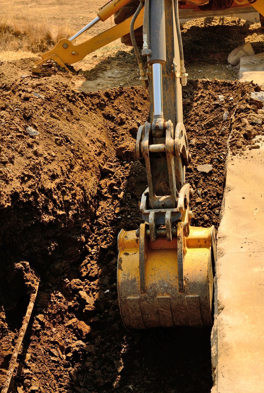 A yellow excavator is digging a hole in the ground