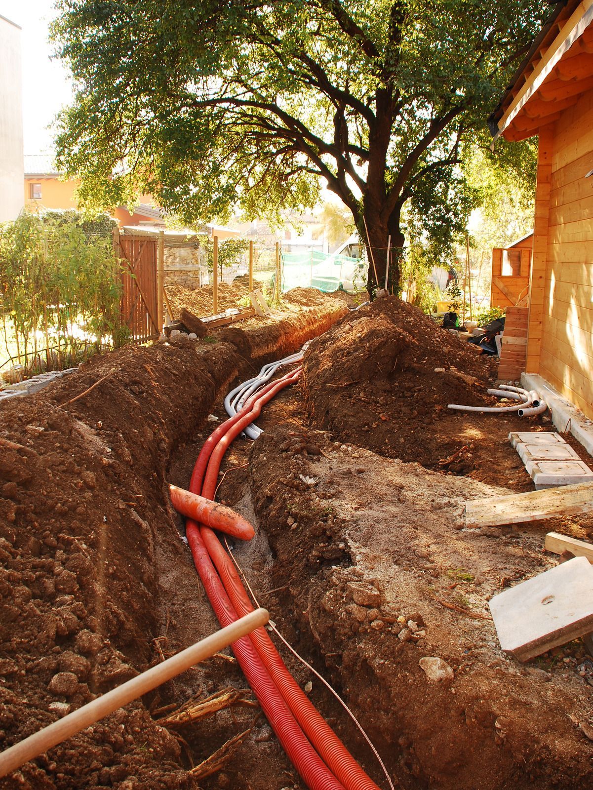 A bunch of orange pipes are laying in the dirt