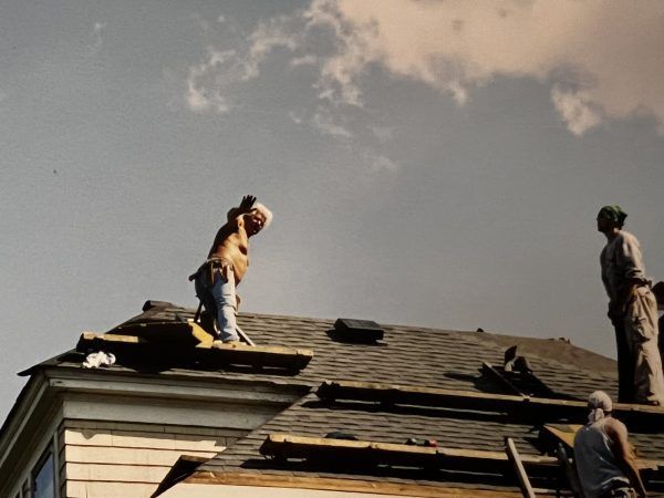 Two men are working on the roof of a house
