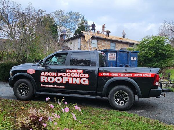 A black truck with the word roofing on the side is parked in front of a house.