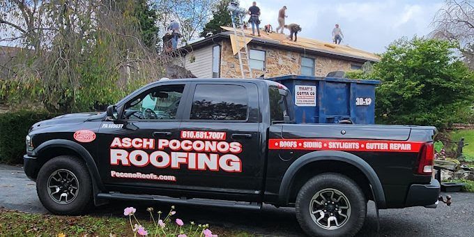 A black truck with the word roofing on the side is parked in front of a house.