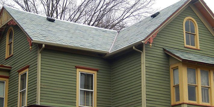 A green house with a gray roof and yellow trim