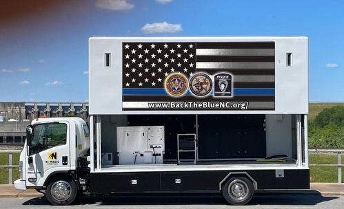 A truck with an american flag on the side is parked on the side of the road.