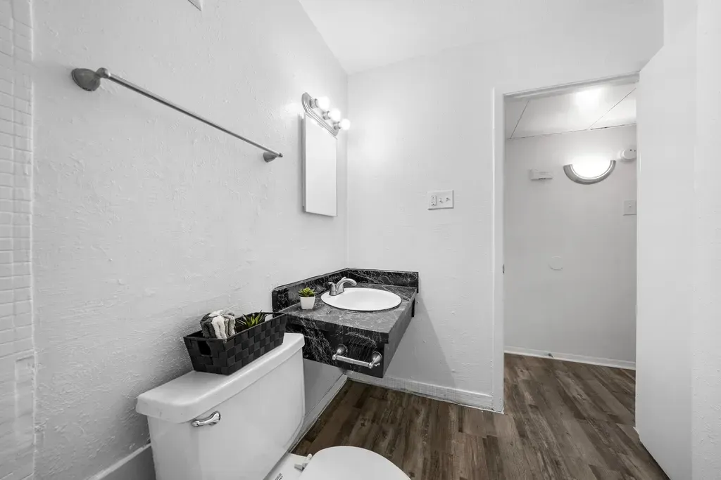A bathroom with a toilet , sink and mirror.