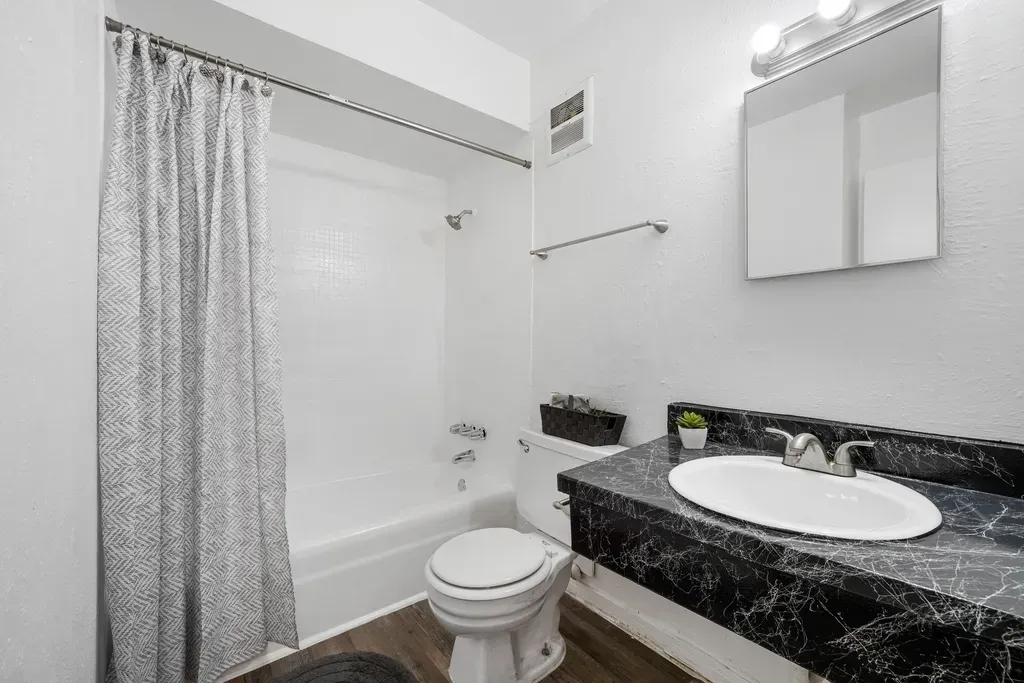 A bathroom with a toilet , sink , bathtub and shower curtain.