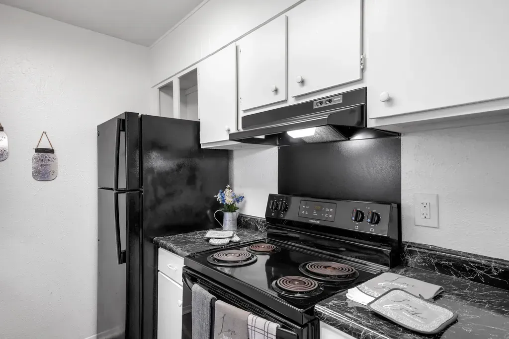 A black and white photo of a kitchen with a stove , refrigerator and dishwasher.