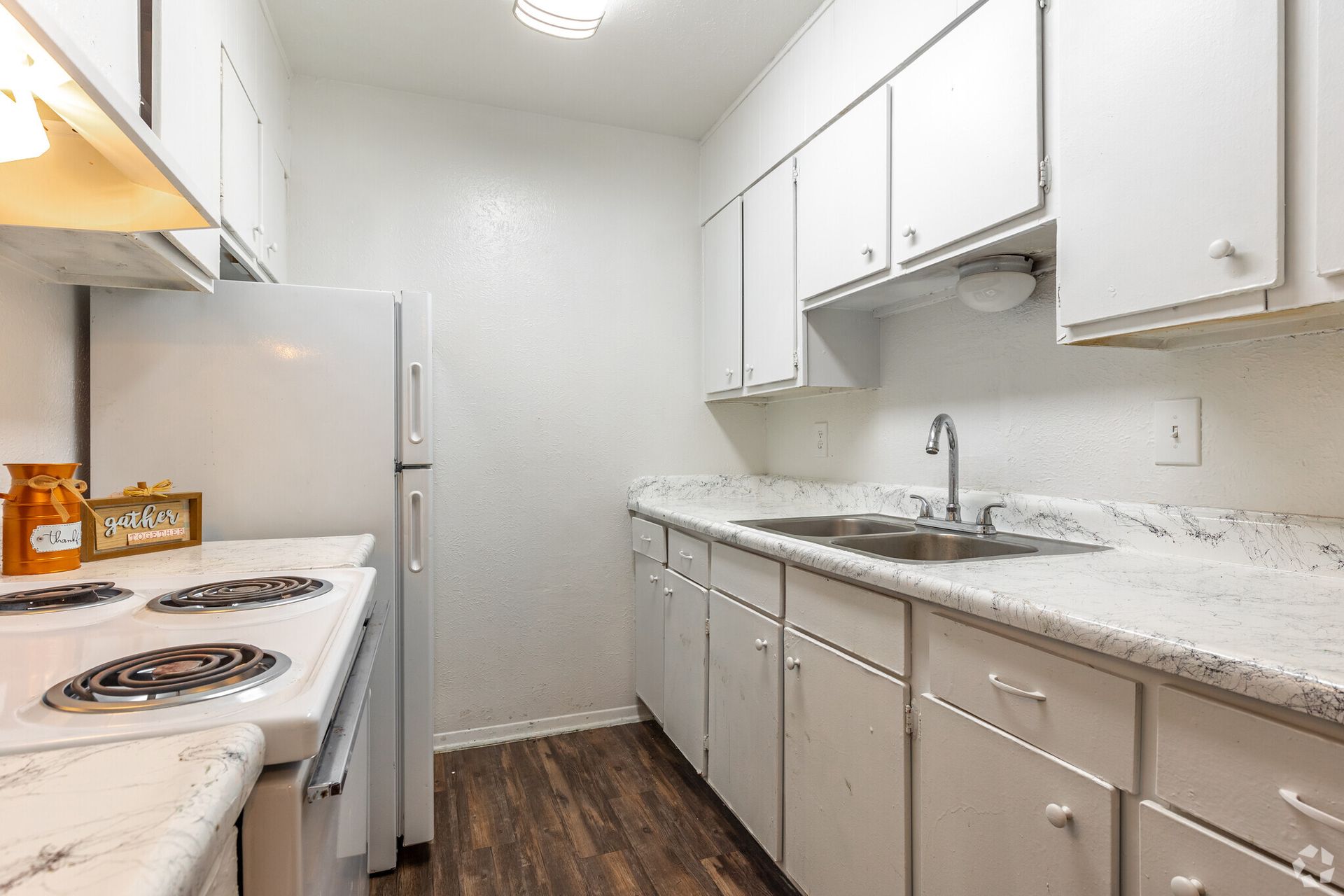A kitchen with white cabinets , a refrigerator , stove , sink and dishwasher.
