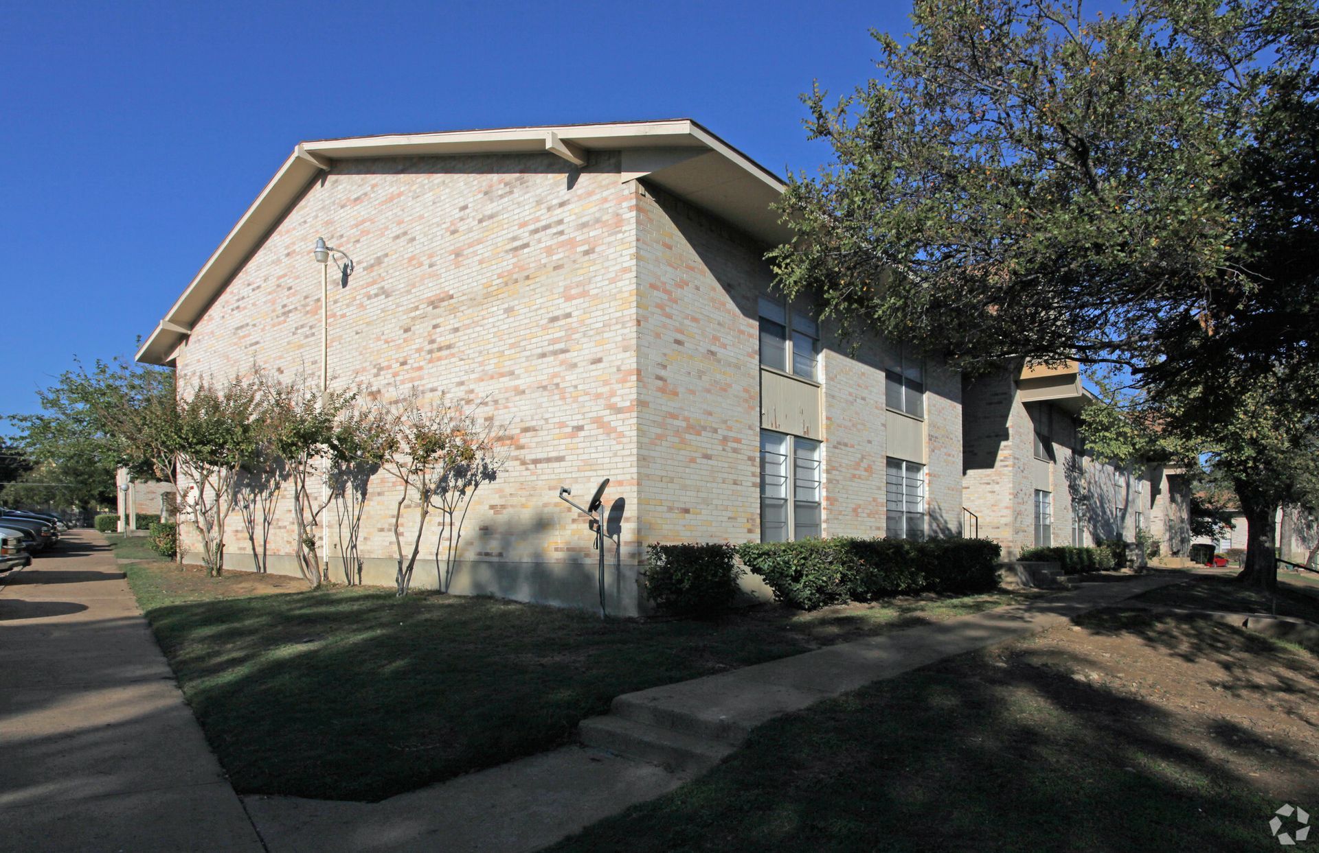 A brick apartment building with trees in front of it