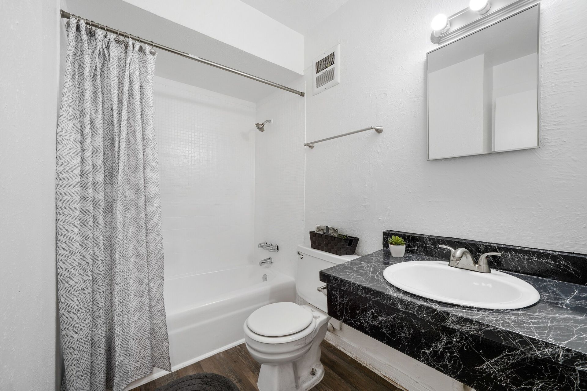 A bathroom with a toilet , sink , bathtub and shower curtain.