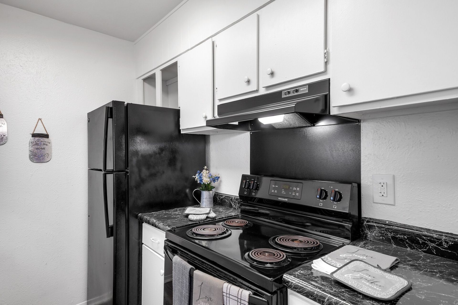 A kitchen with a black refrigerator , stove , and dishwasher.
